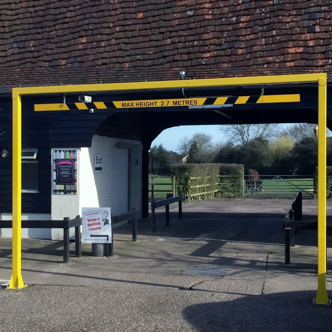 Height restriction barrier with nudge bar